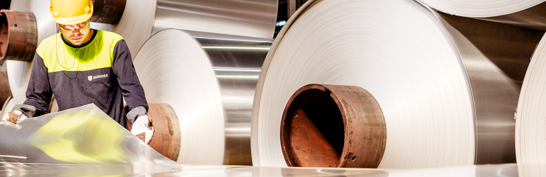 Employee examining flat rolled aluminium.